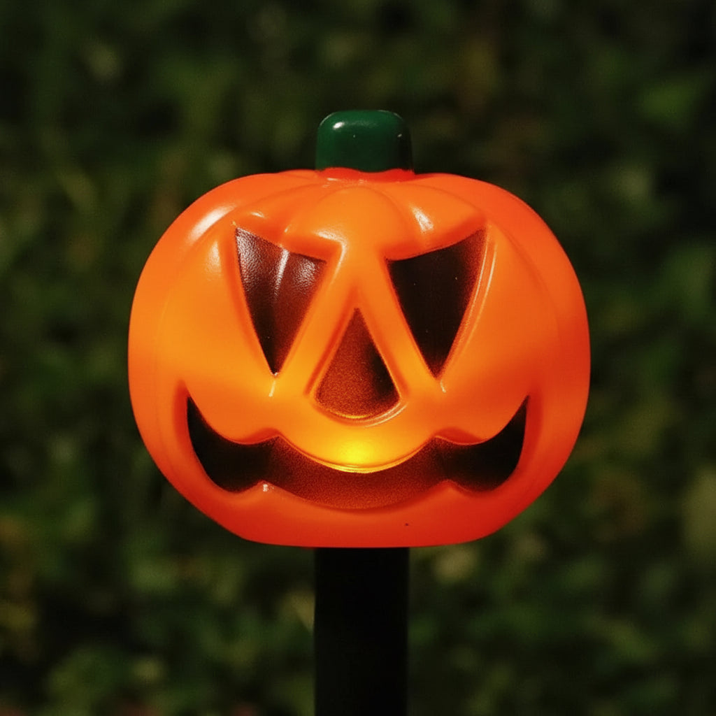 Halloween-themed straw toppers shaped like jack-o'-lanterns on a green leafy background.